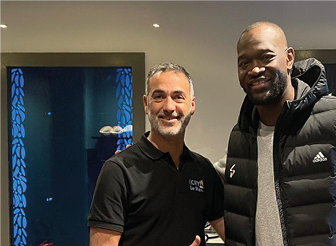 Portrait de Yohann, kinésithérapeute-ostéopathe et associé du Centre Cryothérapies Le Mans. Il pose devant la chambre de cryothérapie corps entier avec un joueur de basket du MSB Le Mans