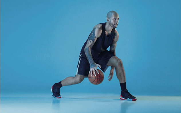 Basketteur tatoué, sur fond bleu, en train de dribbler, illustrant l’amélioration des performances sportives générée par la pratique régulière de la cryothérapie corps entier au Mans