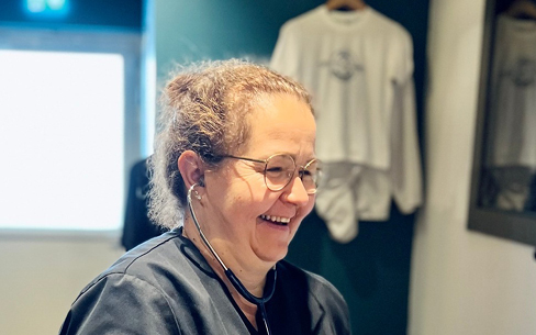 Séverine, l’infirmière du centre Cryothérapies Le Mans en Sarthe, avec un stéthoscope, un grand sourire et habillée d’une blouse.